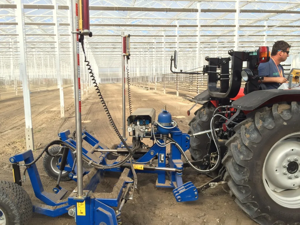 Exemplu de lamă nivelatoare AP tractată de un tractor într-o seră